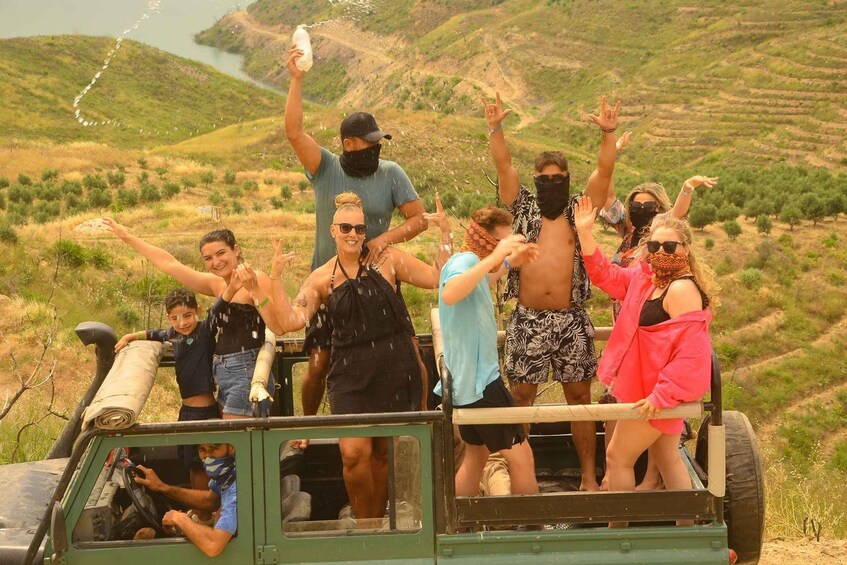 A group of people celebrating on a vehicle in a hilly landscape. 4
