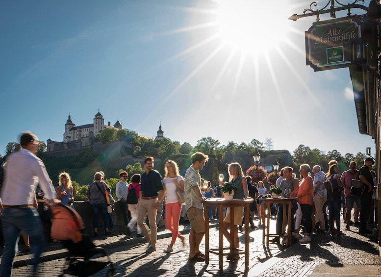 A crowd of people walking on a cobblestone street with a castle in the background. 1