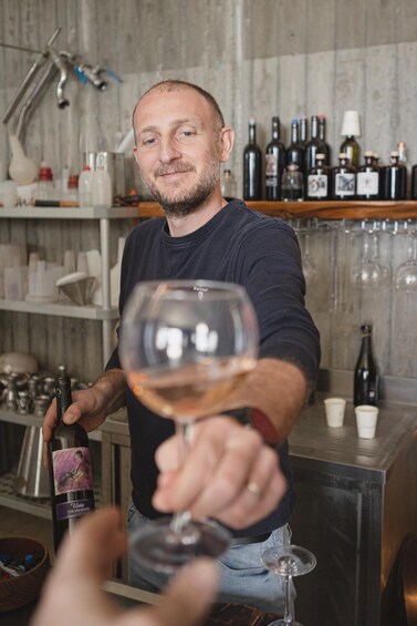 A person holding a wine glass in a bar setting with shelves of bottles and glasses. 4