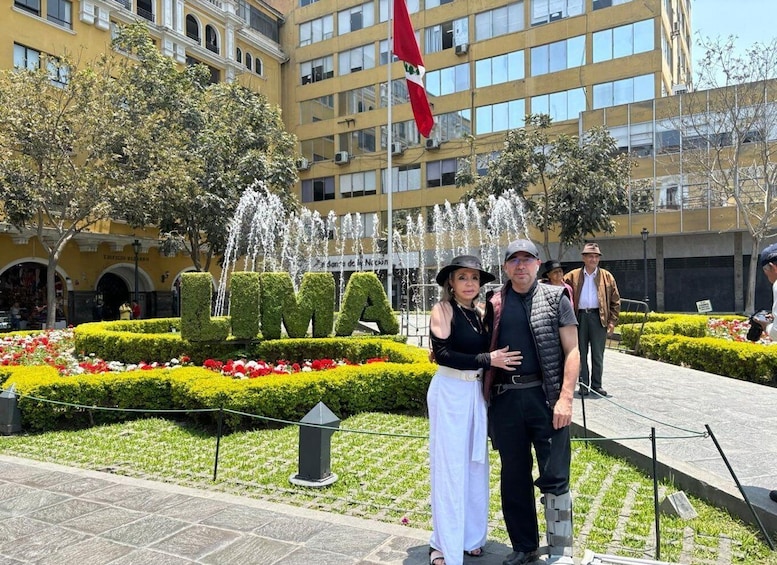 A couple standing in front of a fountain with the word "UMA" spelled out in greenery. 5