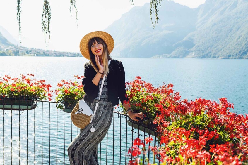 A person standing by a railing with a lake and mountains in the background. 2