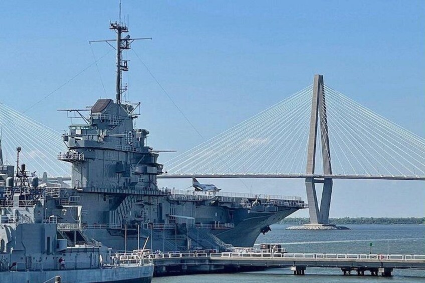A naval ship docked near a cable-stayed bridge. 5