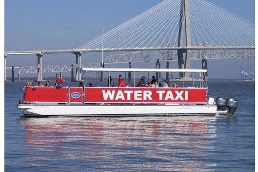 A water taxi with 'WATER TAXI' written on its side, a bridge in the background, and passengers on board. 4