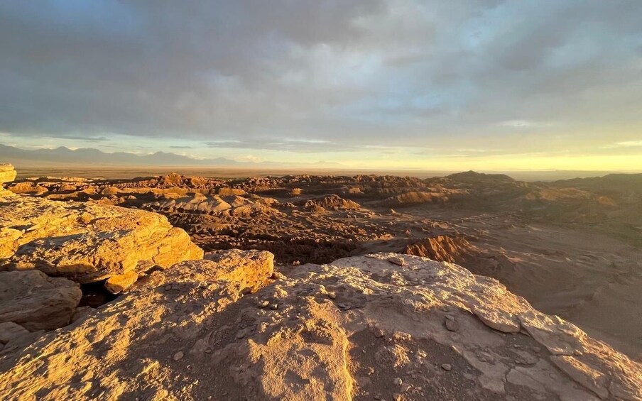 A rugged landscape with rocky terrain and distant mountains under a cloudy sky. 3