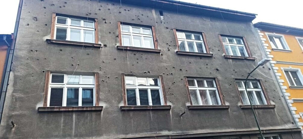 A building with multiple windows and bullet holes. 5