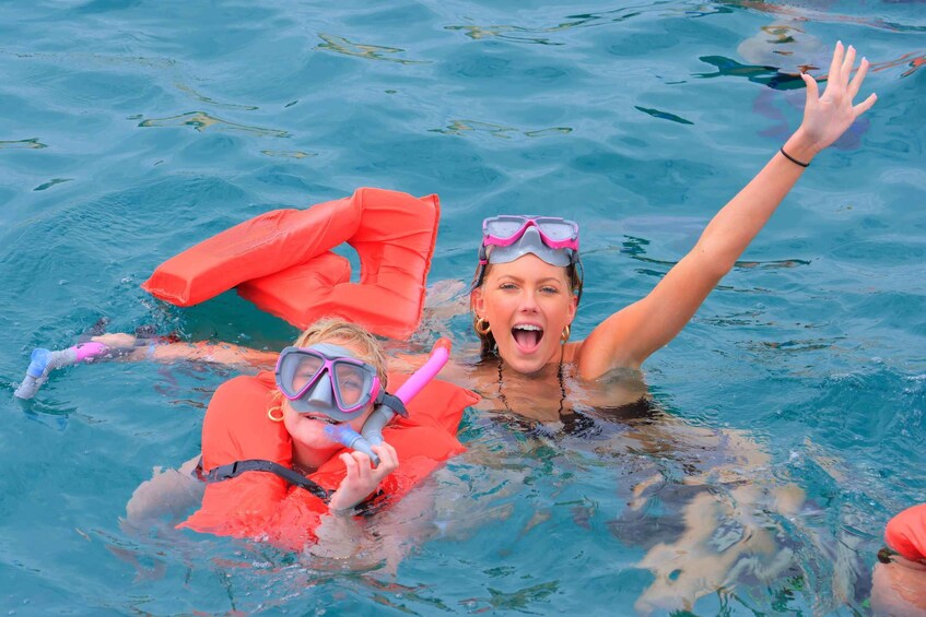Two people swimming in a pool with red life vests and snorkels. 2