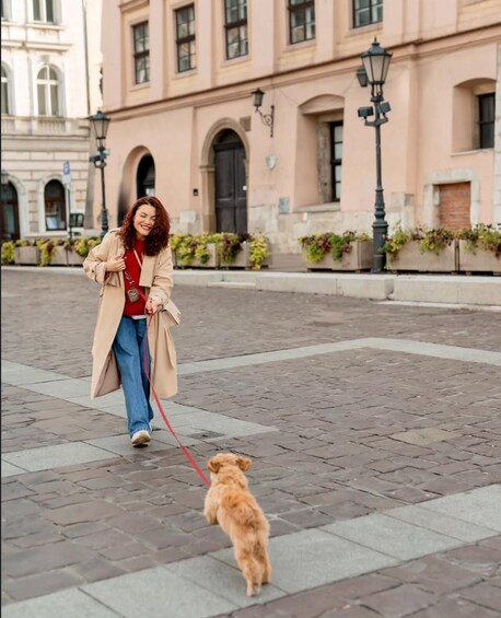 Une personne promène un petit chien sur une place pavée, avec des bâtiments en arrière-plan. 3