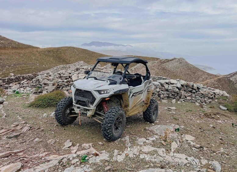 A white Polaris RZR on rocky terrain with mountains in the background. 2