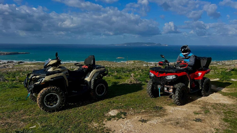 Two ATVs parked on a grassy hill with a coastal view. 3