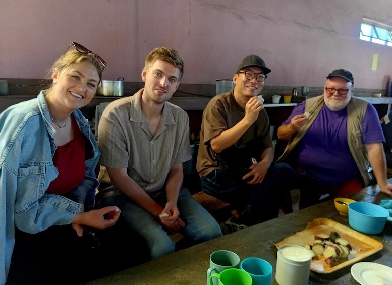Four people sitting at a table with food and drinks. 4