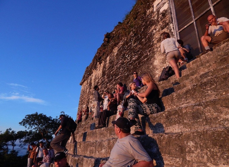 People sitting on stone steps of a historical site. 1