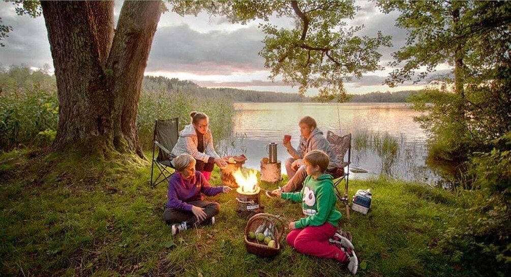 A group of people camping by a lake with a campfire. 1