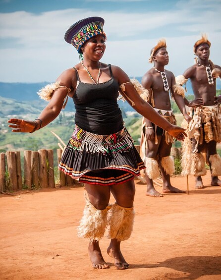A person in traditional attire dancing on a dirt path with a scenic landscape in the background. 4