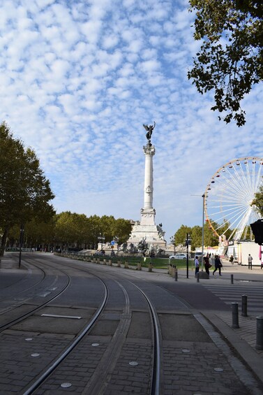 A monument, a Ferris wheel, and a tram track in a park. 3
