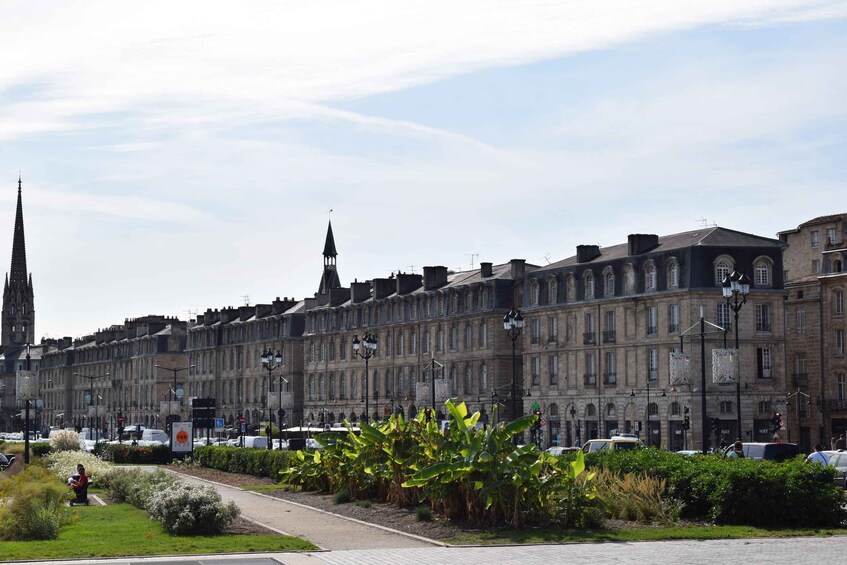 A historic street lined with buildings, including a church spire and a large building with arched windows. 4