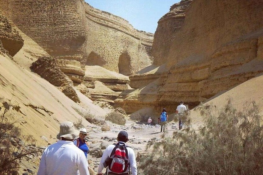 A group of hikers walking through a canyon with layered rock formations. 2
