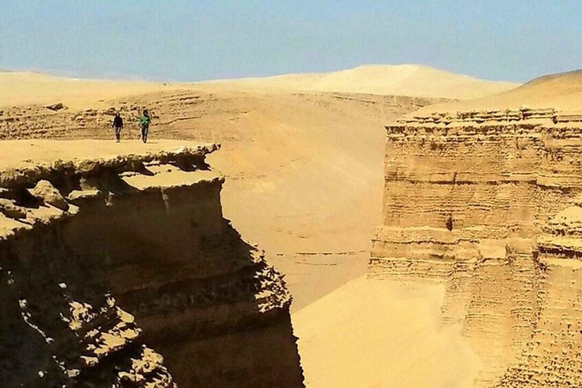 A desert landscape with a cliff and layered rock formations. 3