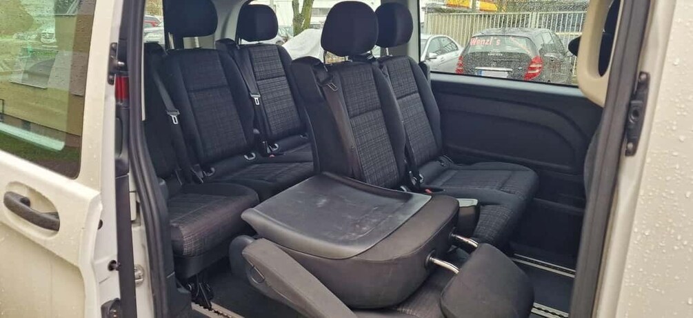 A vehicle interior with a bench seat and three back seats. 5