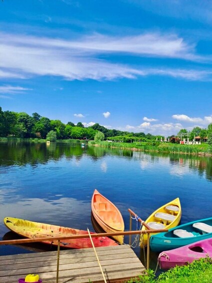 A calm lake with several colorful kayaks docked on a wooden pier. 1