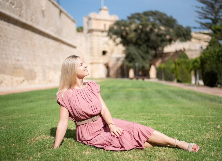 A woman sitting on grass in front of a historic building. 4