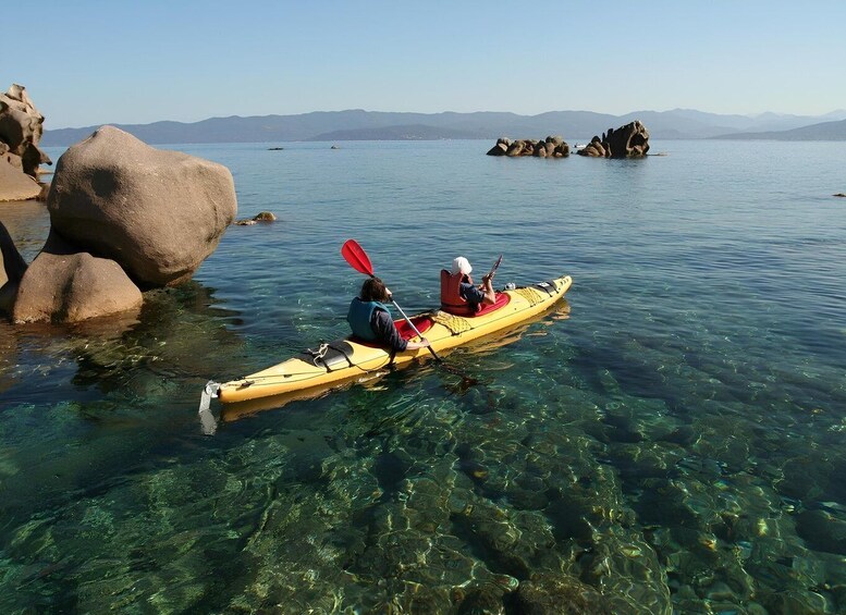 A person kayaking on clear water with rocks and mountains in the background. 3