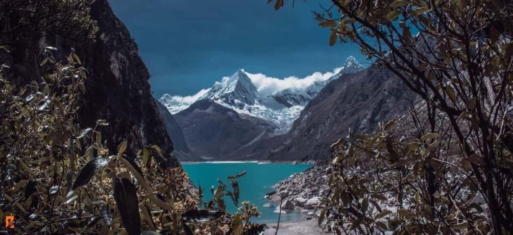 A mountainous landscape with a turquoise lake, snow-capped peaks, and dense foliage. 4