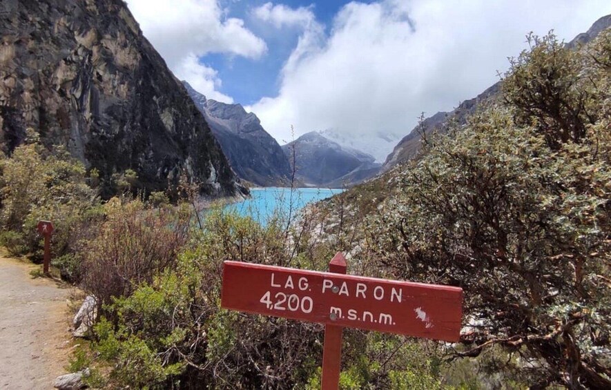 A sign for 'LAG. PARON 4200 m.s.n.m.' with a mountainous landscape and a lake in the background. 2