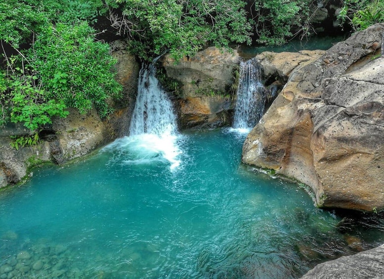 A waterfall in a forested area with clear turquoise water. 3
