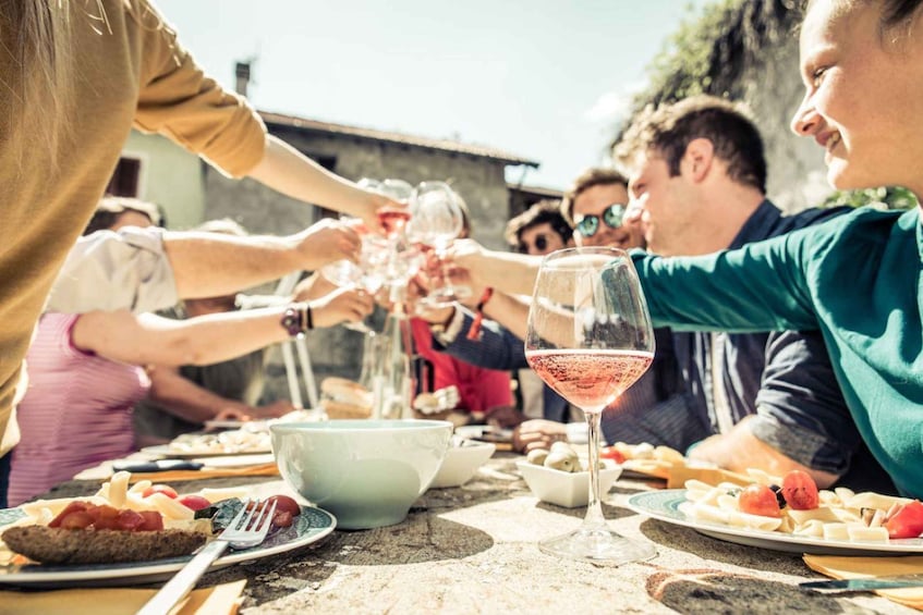 A group of people toasting with wine glasses at a table with food. 1