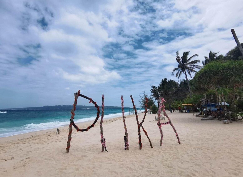 A beach with a wooden arch spelling "MIKA" decorated with flowers. 3