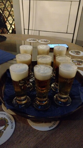 A tray with several glasses of beer on a table. 1
