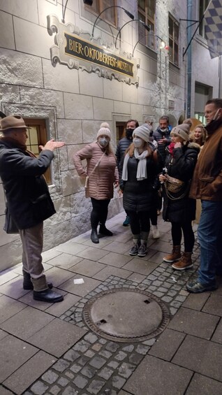A group of people standing in front of a building with a sign that reads "Bier Oktoberfest Museum". 5