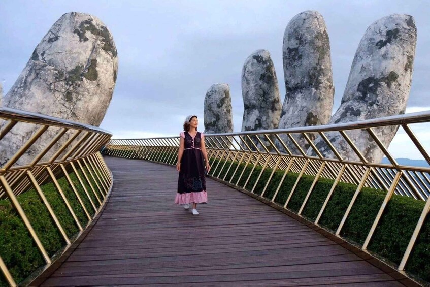 A woman walking on a wooden bridge with large rock formations on either side. 4