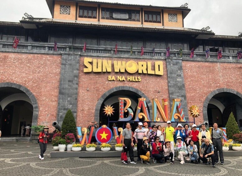 A group of people in front of the Sunworld Ba Na Hills entrance with a large 'BAN' sign. 3