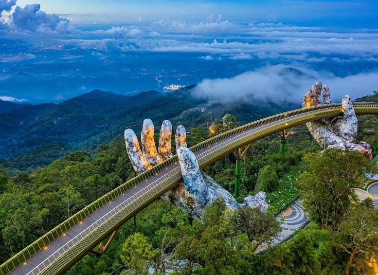 A bridge with a unique hand-shaped design, surrounded by lush green forest and mountains. 5