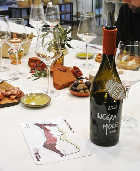 A bottle of 2024 Negra Mole Tinto wine, a map of Algeria, and various food and drink items on a table. 4