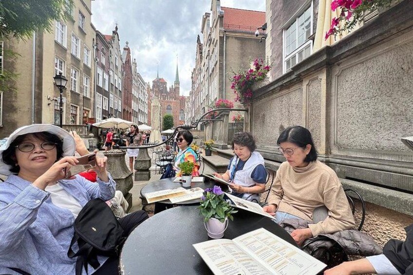 A group of people sitting at a table outdoors, reading a menu. 2
