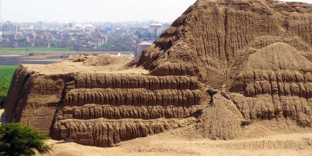 A large, ancient stepped pyramid structure with a cityscape in the background. 5