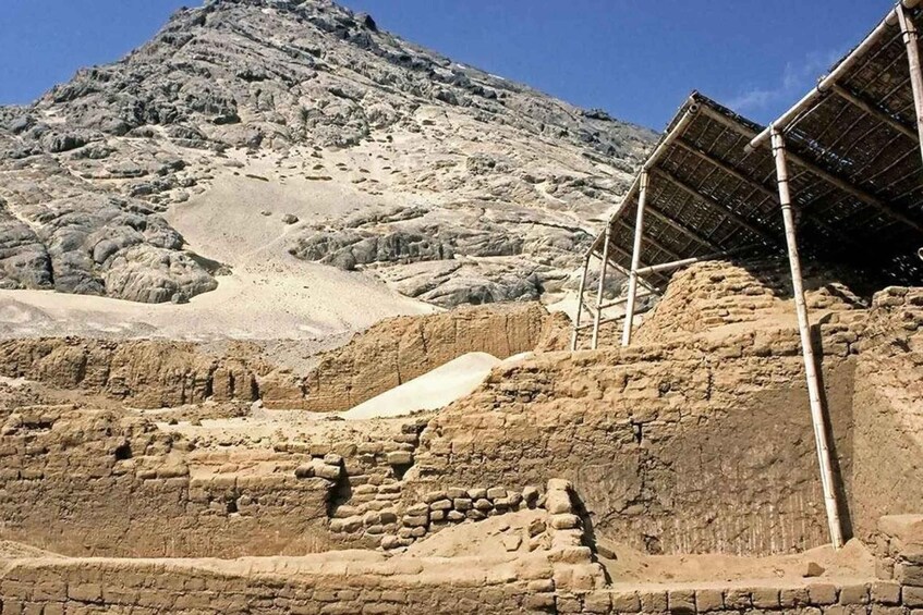 Ancient ruins with a large rock formation in the background. 4