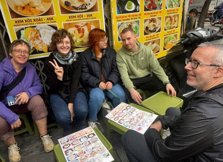Four people sitting on a bench with a food menu in front of them. 4