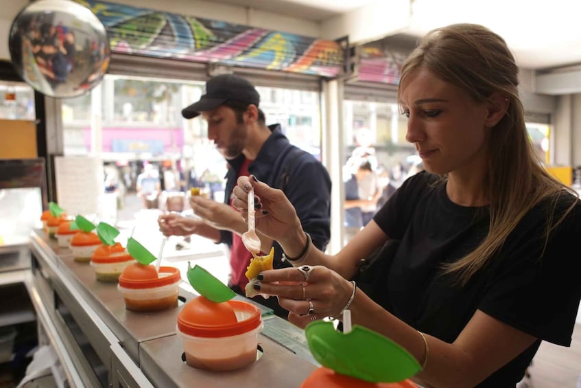A person preparing a drink with a spoon in a food stall. 1