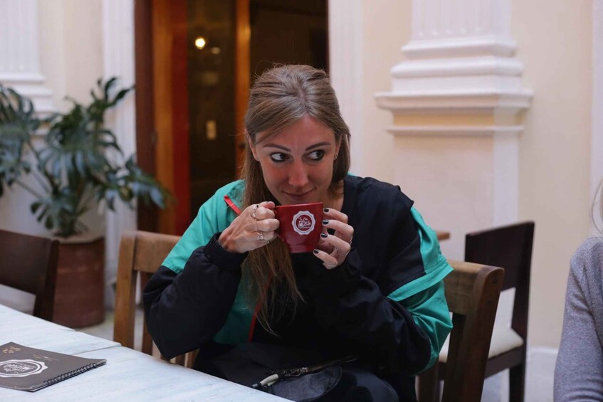 A person sitting at a table with a notebook and a red mug. 4