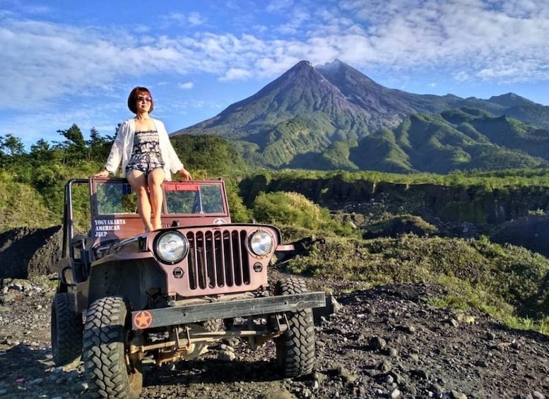 A person in a jeep on a rocky terrain with a volcano in the background. 1
