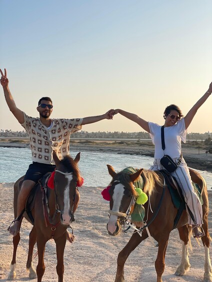Two people on horseback making a heart shape with their hands. 1