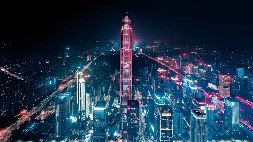 A cityscape at night with a prominent skyscraper illuminated in pink. 5