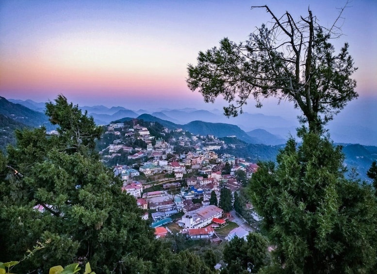 A mountainous town with buildings nestled among trees, under a twilight sky. 5