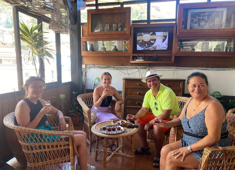 A group of people sitting at a table with drinks, surrounded by wicker furniture and a television. 5