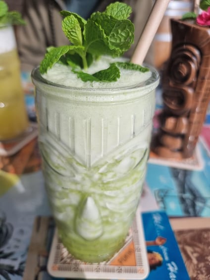 A glass of green smoothie with mint leaves on a coaster. 3