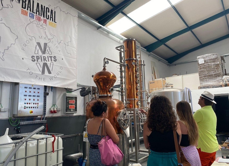 A distillery with copper stills and a large banner advertising spirits. 1
