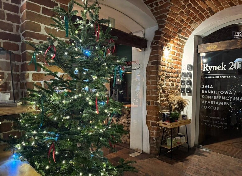 A Christmas tree with lights and ribbons in a brick building. 2